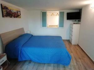 um quarto com uma cama azul e uma televisão em Serendipity em Catânia