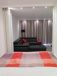 ein Wohnzimmer mit einem schwarzen Sofa und einem Bett in der Unterkunft Ferienpark Sierksdorf App 483 - Strandlage in Sierksdorf
