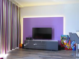 ein Wohnzimmer mit einem Flachbild-TV an einer lila Wand in der Unterkunft Ferienpark Sierksdorf App 483 - Strandlage in Sierksdorf