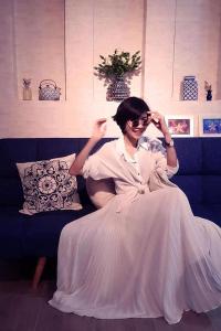 a woman in a white dress sitting on a couch at Zleepinezz Hostel in Phra Nakhon Si Ayutthaya