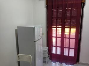una cucina con frigorifero e tenda rossa di Appartamento di 70mq arredato a 600m dal Mare a Scalea