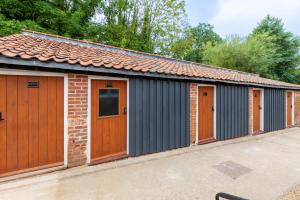 eine Reihe von Garagen mit Holztüren auf einem Parkplatz in der Unterkunft The Georgian - Norfolk Cottage Agency in East Dereham