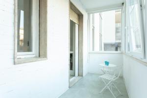 ein weißes Zimmer mit einem weißen Stuhl und Fenstern in der Unterkunft Cozy Flat Romeo Menti - Vicenza in Vicenza