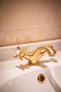 einen goldenen Wasserhahn auf einem weißen Waschbecken in der Unterkunft ApartOne Land-Hotel in Sebnitz