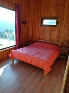 Las Bandurrias Eco Hostal في كوشامو: سرير في غرفة خشبية مع نافذة كبيرة