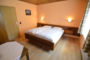 a bedroom with a large bed with white sheets at Landgasthof Grüner Baum in Regnitzlosau