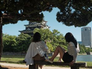 two women sitting on a bench in front of a tower at FAV HOTEL HIROSHIMA STADIUM in Hiroshima