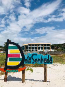 un cartel en la playa con un edificio en el fondo en Pousada Dotô Sonhadô Beach en Pontas de Pedra