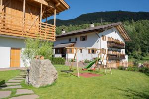 una casa con un cortile con una roccia e un parco giochi di Fortschöllhof a Castelrotto