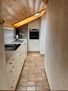 a kitchen with white cabinets and a tile floor at Ferienwohnung am Chiemsee in Übersee