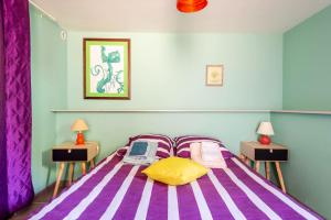 a bedroom with a bed with purple and yellow pillows at Maison charmante à Auriol avec piscine privée in Auriol
