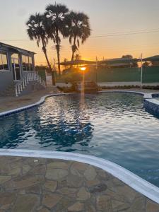 uma grande piscina com um pôr-do-sol ao fundo em TETE PALM HOTEL em Tete