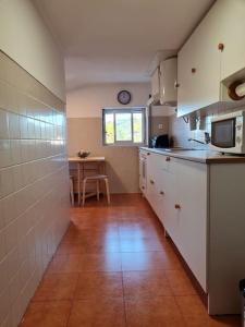 a kitchen with white cabinets and a table in it at Alojamento 3 vistas in Sintra