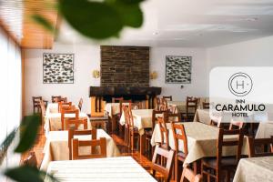 un restaurante con mesas y sillas y una chimenea en Inn Caramulo Hotel, en Tondela