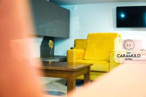 a living room with a yellow chair and a coffee table at Inn Caramulo Hotel in Tondela