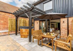 un patio avec une table et un parasol dans l'établissement Roe Cottage - Disabled adapted - 2 bed - hot tub, à Alcester