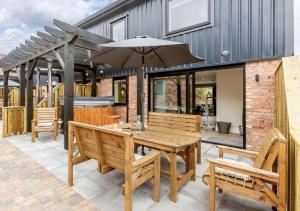 a patio with a wooden table and chairs and an umbrella at Fawn Cottage disabled adapted 3 bed cottage in Coughton