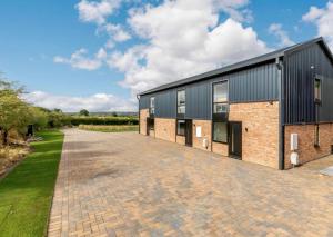 a brick and black building with a driveway at Buck Cottage disabled adapted 3 bed cottage in Alcester