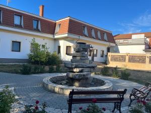 a fountain in front of a building with a bench at HOTEL Kuruc Panzio TARPA Kossuth utca 25E 