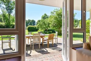 a patio with a table and chairs looking out into the yard at Bell Meadow in Coldwaltham