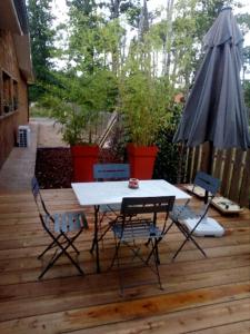 einen Tisch, Stühle und einen Regenschirm auf einer Holzterrasse in der Unterkunft La cabane de marie in Arès