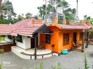 a small orange house with a red roof at Golden Peak Estate Homestay in Wayanad