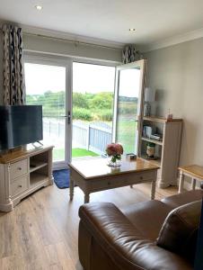 a living room with a couch and a tv and a table at Poppy Annex in Wellow