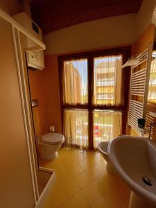 La salle de bains est pourvue de toilettes, d'un lavabo et d'une fenêtre. dans l'établissement Residence Corte della Vittoria, à Parme