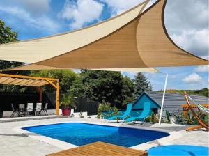 a large wooden umbrella over a swimming pool at Völgyhíd Vintage Apartman in Pusztaszemes