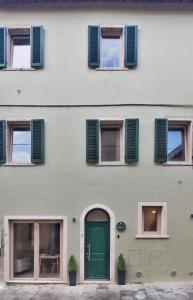 un edificio con una puerta verde y ventanas en A Casa di BiaGio en Rapolano Terme