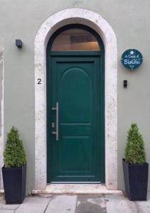 uma porta verde num edifício com dois vasos de plantas em A Casa di BiaGio em Rapolano Terme