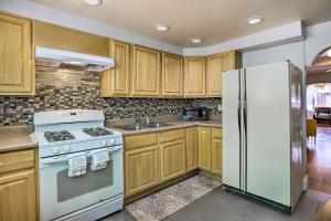 a kitchen with wooden cabinets and a white refrigerator at South Philly Townhome 3 Mi to Center City in Philadelphia