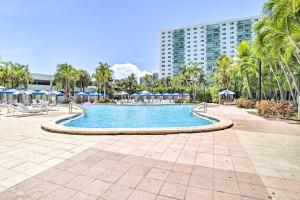 a swimming pool with palm trees and a building at Sunny Isles Resort Condo Less Than Half-Mi to Beach! in Miami Beach