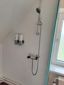 a shower with a shower head on a wall at Bjergby Guesthouse in Hjørring