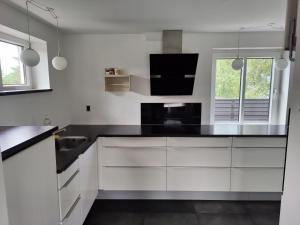 约灵Bjergby Guesthouse的厨房配有白色橱柜和黑色台面