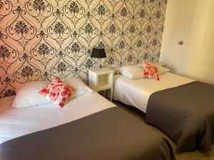 a hotel room with two beds and a wall at Hotel Au Chapon Fin in Poitiers