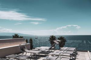 a row of chaise lounge chairs on a balcony overlooking the ocean at MARINO WELLNESS in Ali Terme