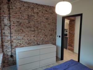 a bedroom with a brick wall and a white dresser at Apartament Loftowy Głuszyca in Głuszyca