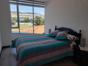um quarto com uma cama e uma grande janela em Hermoso departamento, céntrico y tranquilo em Quito