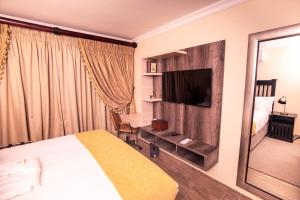 Masingitana Hotel في Acornhoek: غرفة فندقية بسرير وتلفزيون بشاشة مسطحة