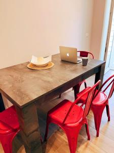 uma mesa de madeira com cadeiras vermelhas e um computador portátil em Locus Amoenus Apartment a pochi passi dagli Scavi em Pompeia