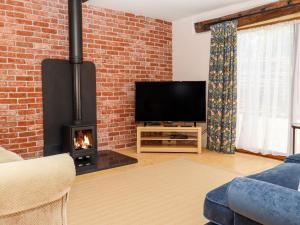 a living room with a fireplace and a tv at Baa Lamb Cottage in Burmarsh