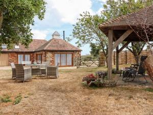 een stenen huis met een tafel en stoelen in een tuin bij Baa Lamb Cottage in Burmarsh