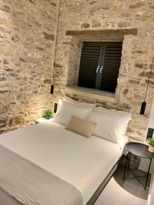 a bedroom with a large white bed in a stone wall at The Backyard in Éva