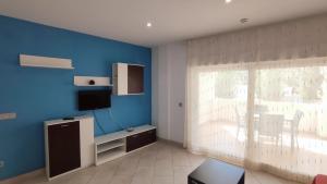 sala de estar con TV y pared azul en Apartamentos Cala Azul La Móra en Tarragona