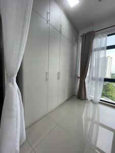 a kitchen with white cabinets and a large window at Kyra Homestay Centrus SOHO Cyberjaya *wifi and pool* in Cyberjaya