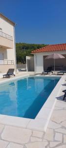 uma piscina com duas cadeiras e um guarda-sol em Villa Ana perfect for families with kids and groups,House with heated Pool em Podstrana