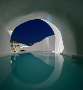 a swimming pool with a white building and water at Lotus Cave Villa in Fira