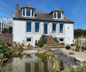 a house with a pond in front of it at The Waterside Rooms in Annan