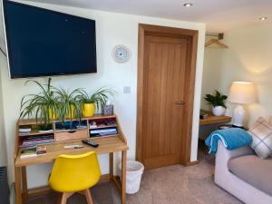 sala de estar con mesa y TV en la pared en The Waterside Rooms, en Annan